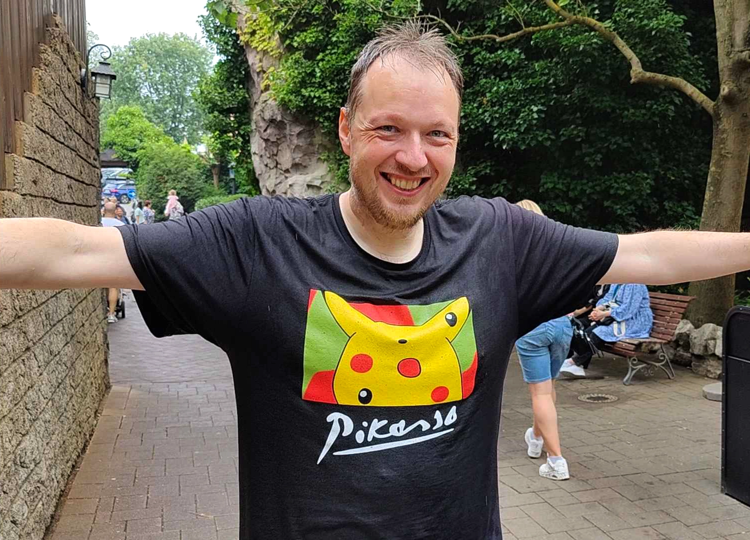 Grumpmeister with arms wide open at a theme park, soaked from a water ride